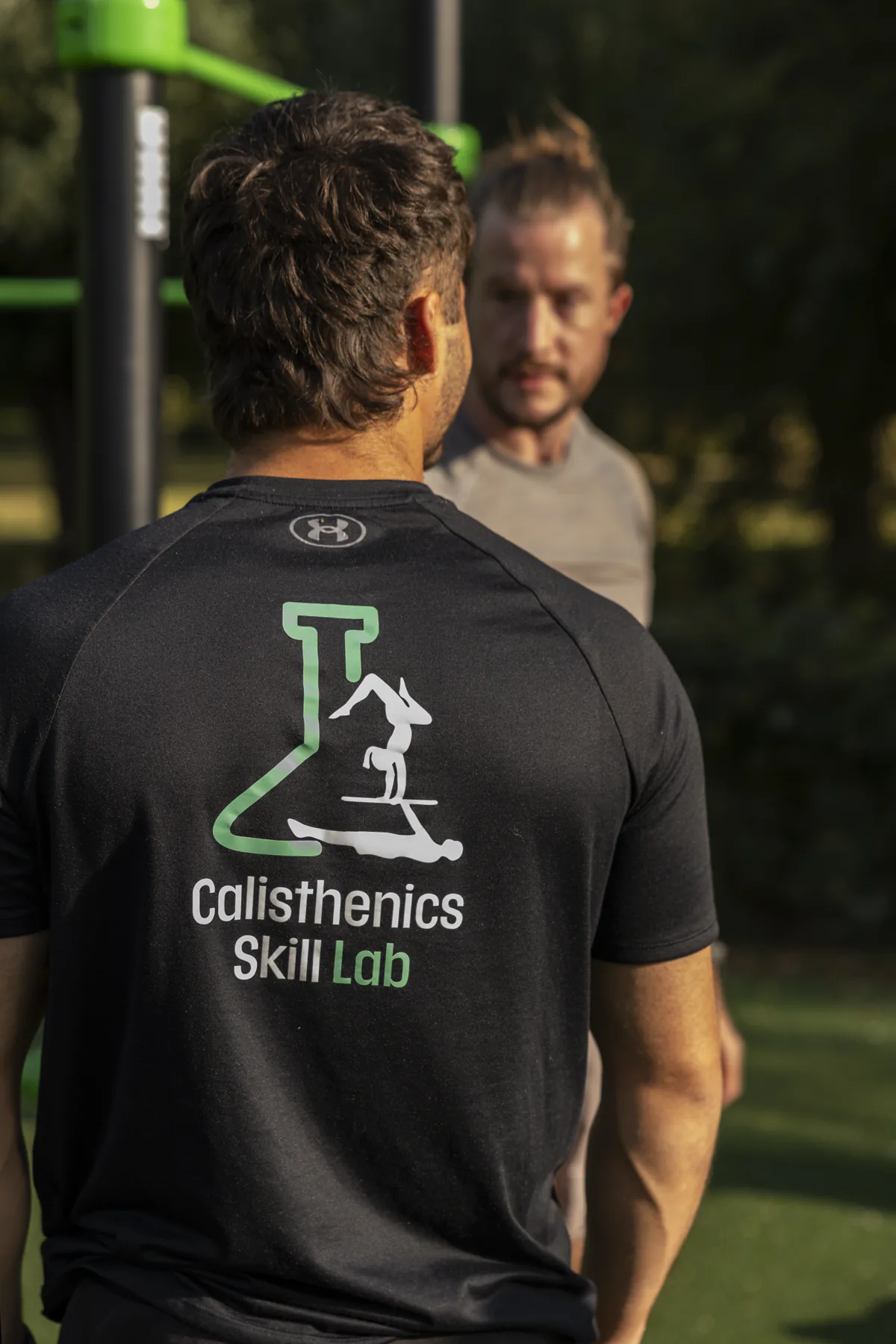 Coach Bryan begeleidt één deelnemer tijdens een personal training in het park